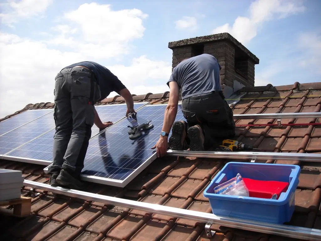Zwei Monteure befestigen ein Solarmodul auf einem Ziegeldach